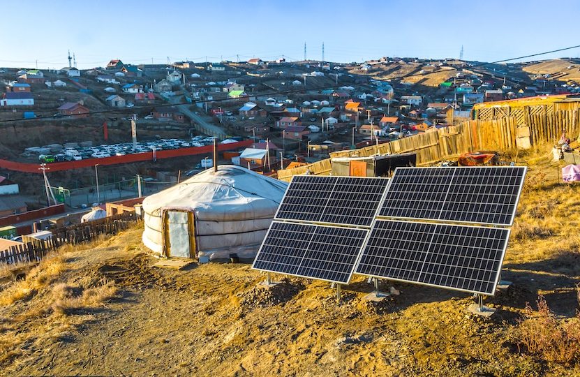 Solar panels beside a yurt on a hillside above a town
