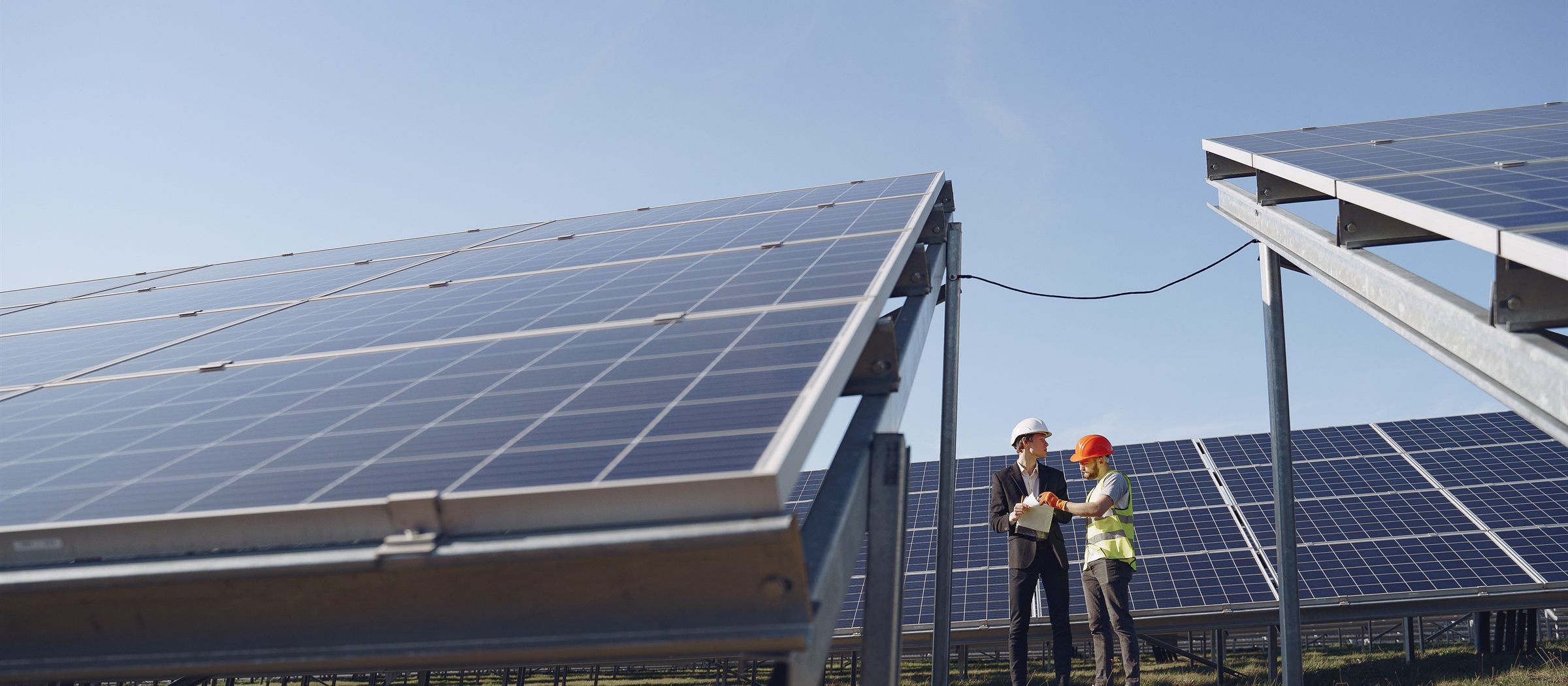Two technicians inspecting rows of solar panels